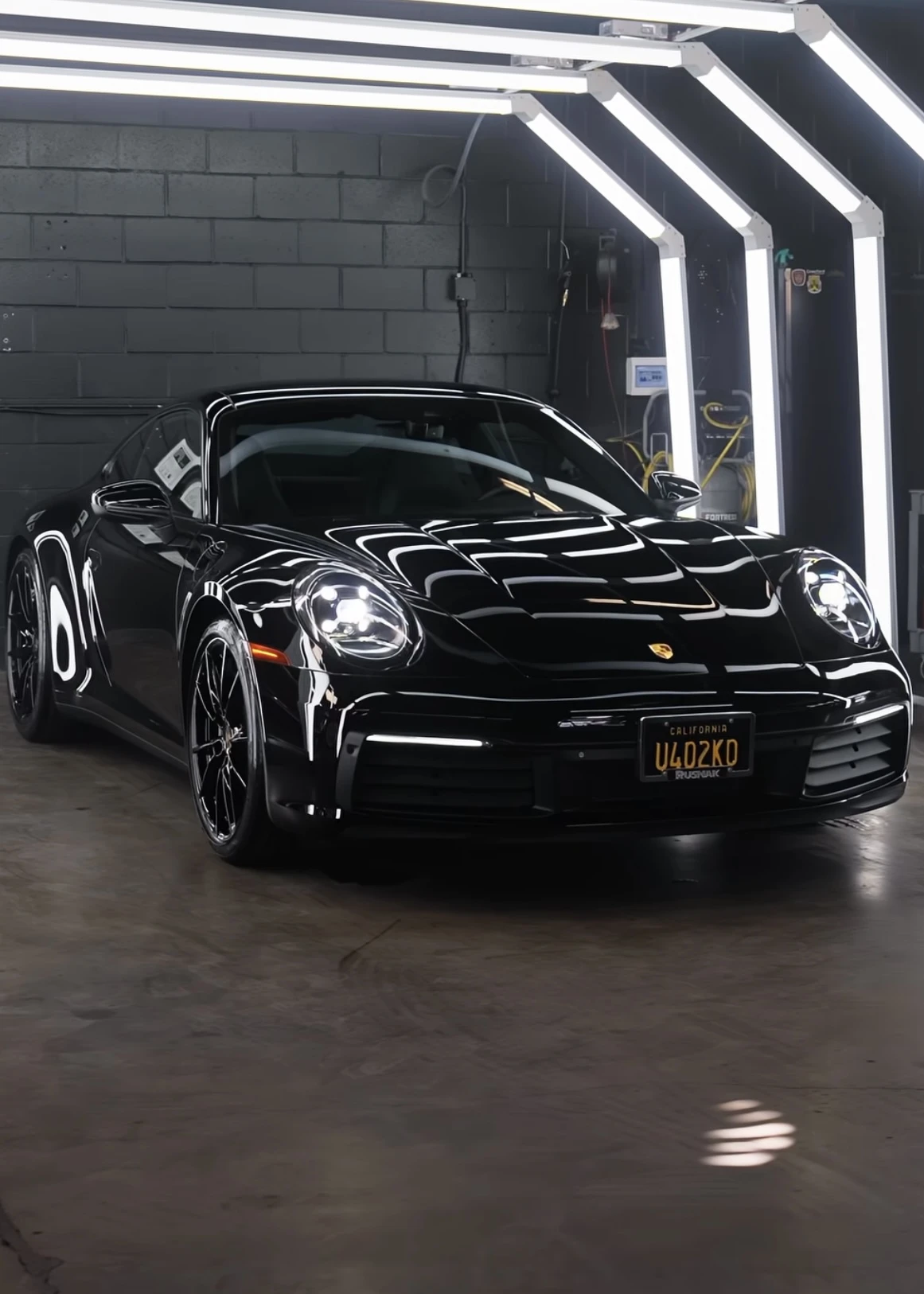 Black Porsche reflecting the detailing studio lights